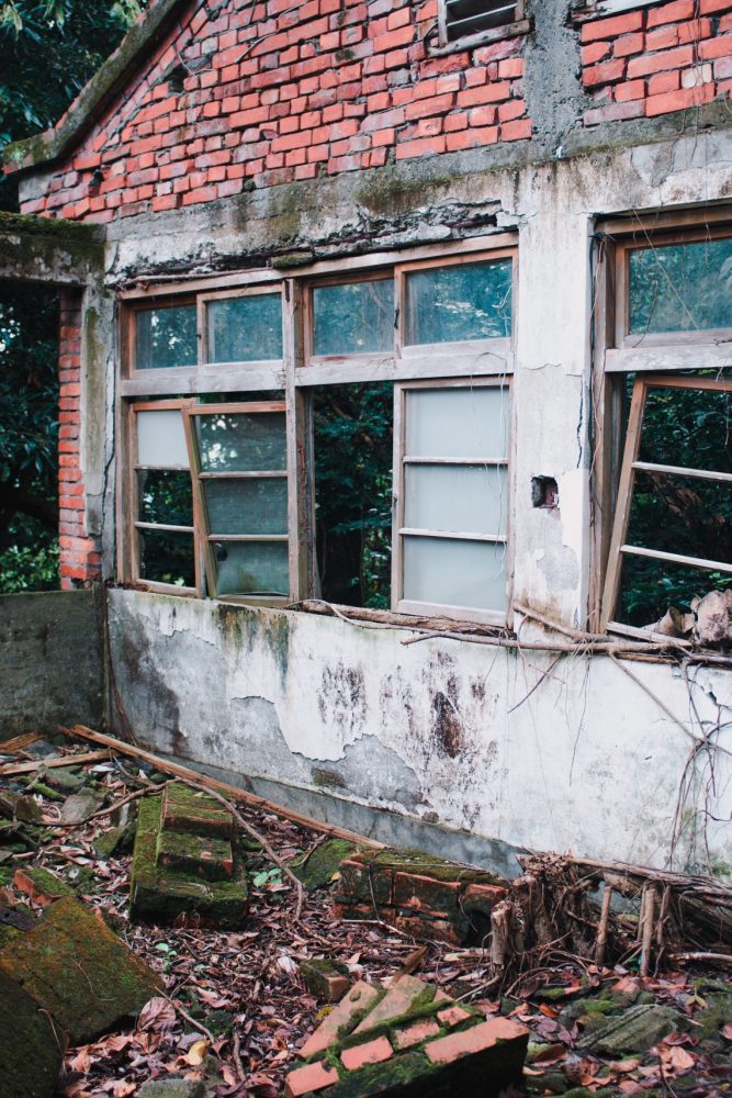 An abandoned old building with destroyed windows in the forest